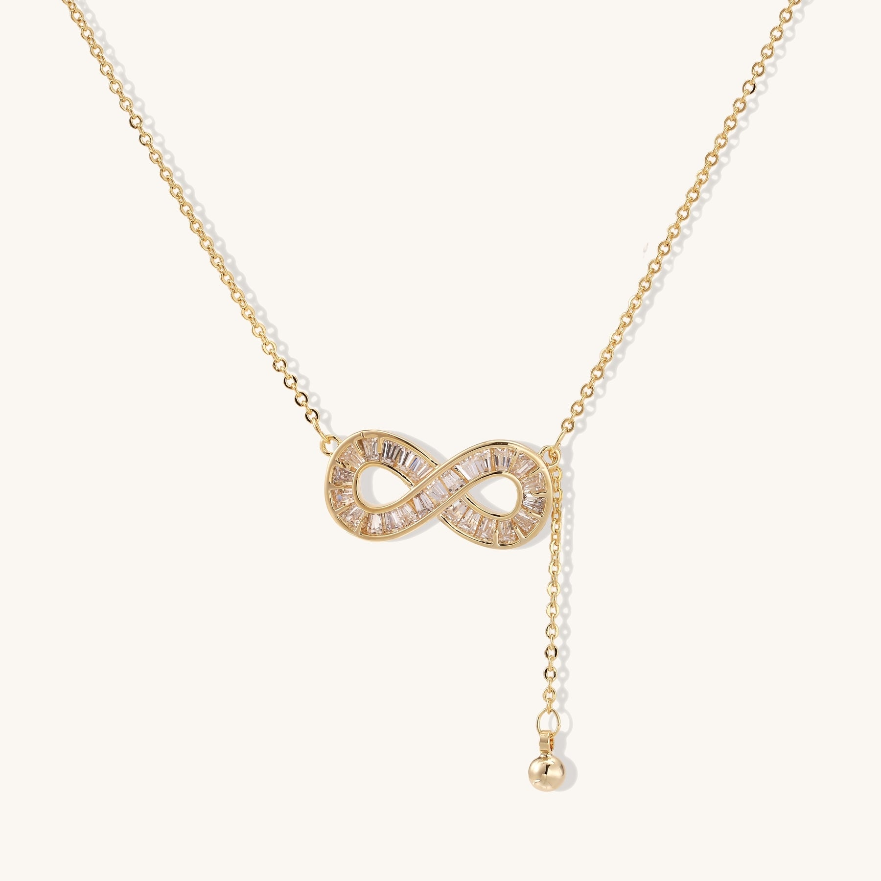 Delicate 14K gold plated infinity pendant with crystal accents on adjustable chain with small ball charm detail.