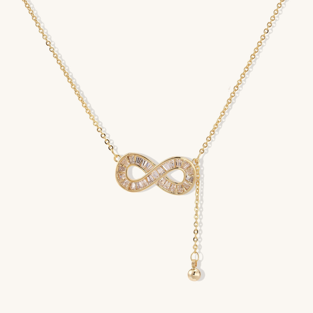 Delicate 14K gold plated infinity pendant with crystal accents on adjustable chain with small ball charm detail.